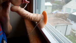 Slutty redhead teases her neighbor by sticking dildo dick on window and fucking it