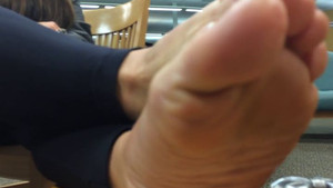 Mysterious mother sits on the chair and puts her beautiful feet on the table